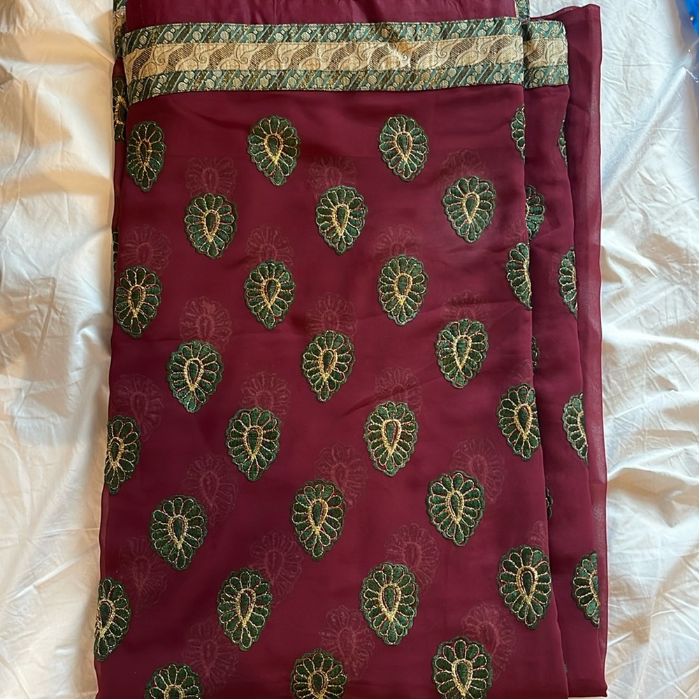 Maroon sari with green thread work all around.